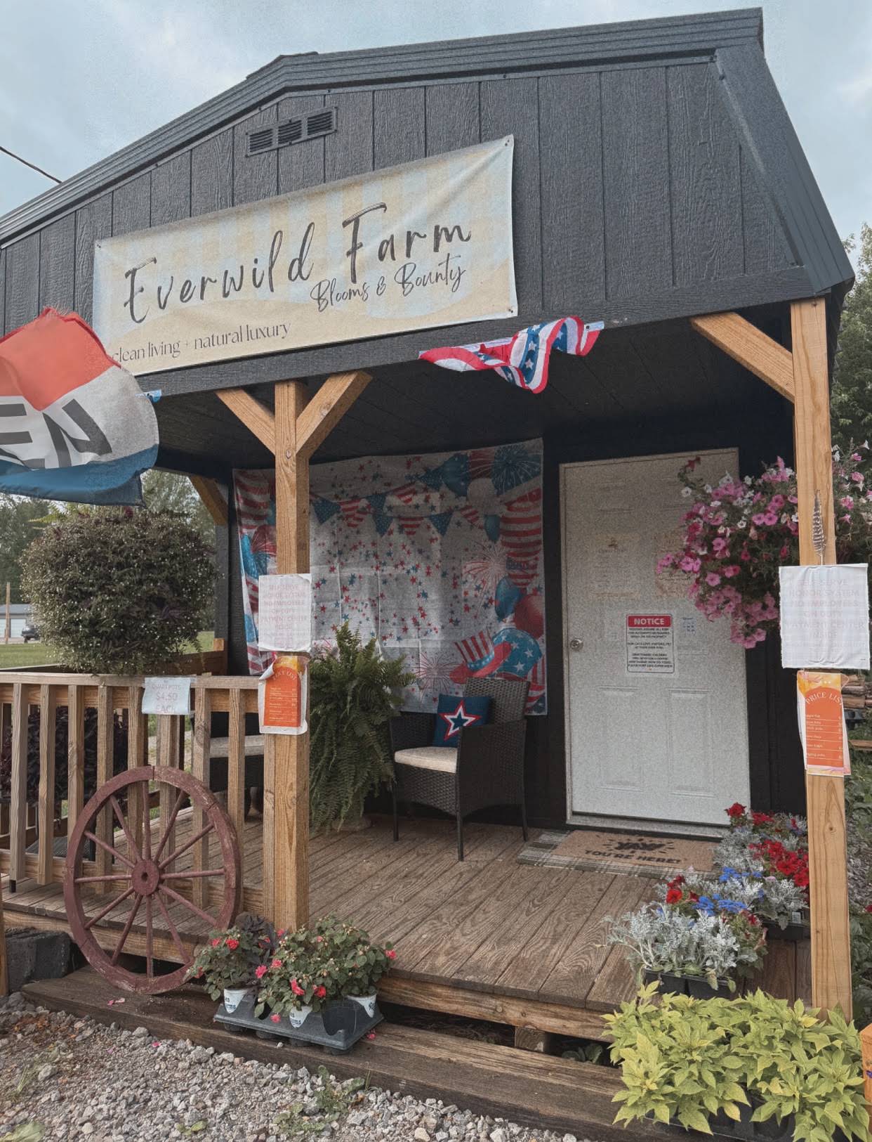 The Everwild Farm market building with its porch, hanging flower baskets, and clean living + natural luxury banner
